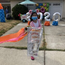 A girl in pink shirt holding shopping cart.