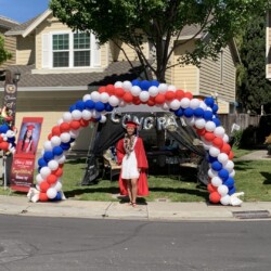 A person standing under an arch with balloons.