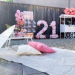 A birthday party with balloons and pink flowers.